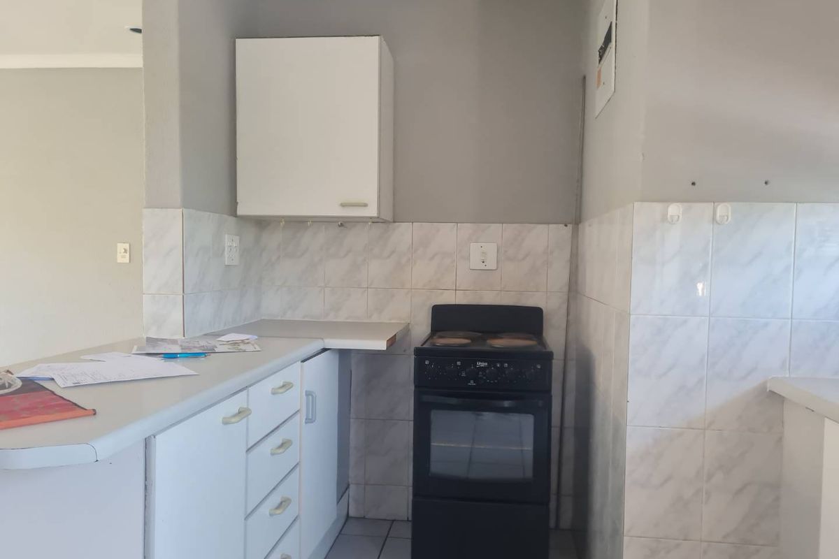 A functional kitchen area featuring white cabinetry, tiled backsplash, and a freestanding stove, offering a practical layout for daily cooking needs.