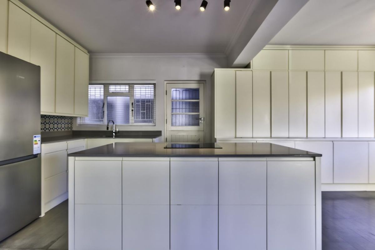 Modern kitchen featuring a central island, extensive built-in cabinetry, integrated cooktop, and sleek finishes, providing a clean and functional culinary space.