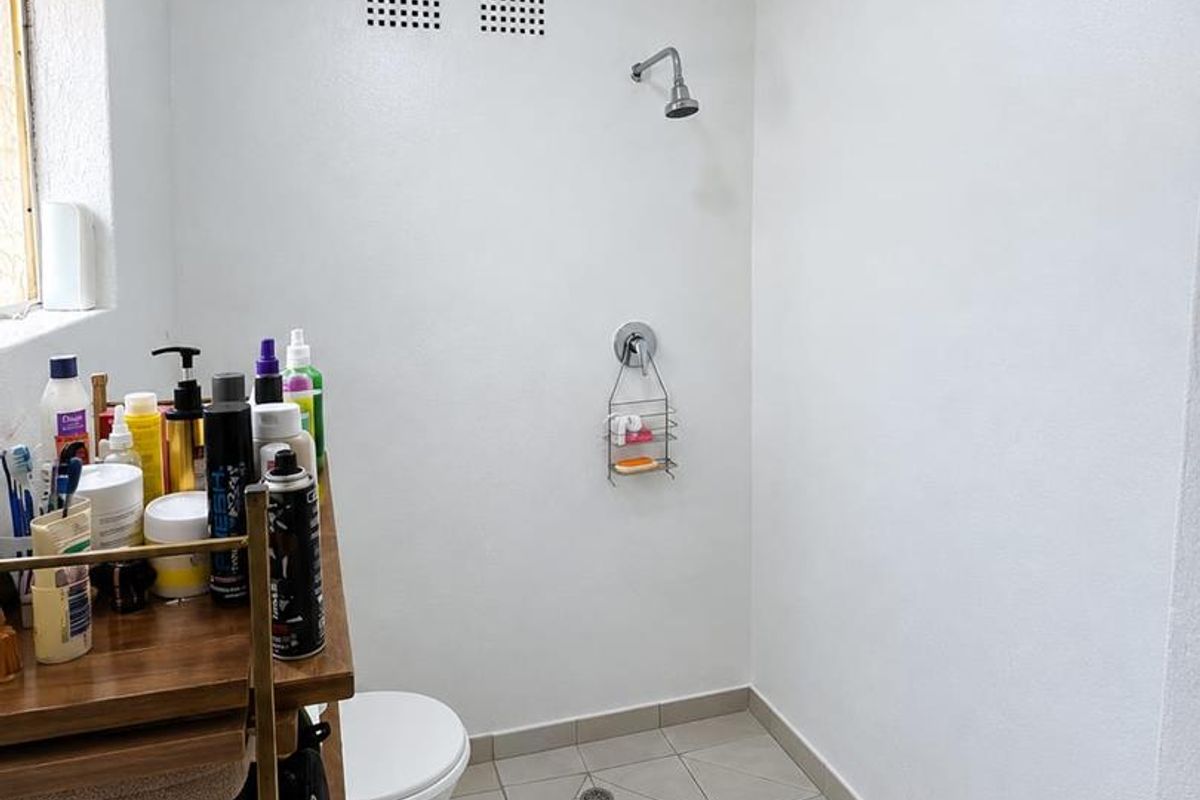 A functional bathroom featuring a walk-in shower area, toilet, and tiled flooring. The space requires minor ceiling repairs.