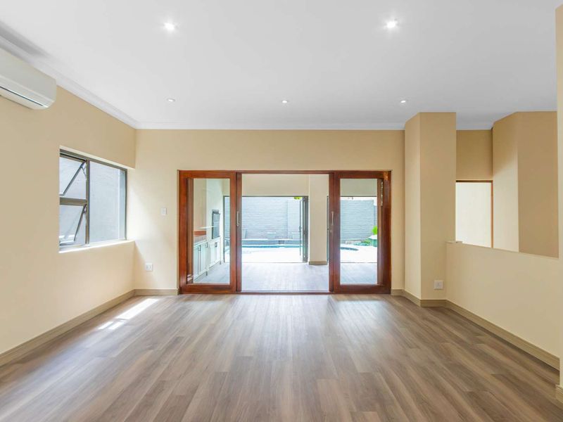 Spacious, light-filled living area featuring modern laminate flooring, recessed lighting, and timber sliding doors providing seamless access to the outdoor patio and pool area.