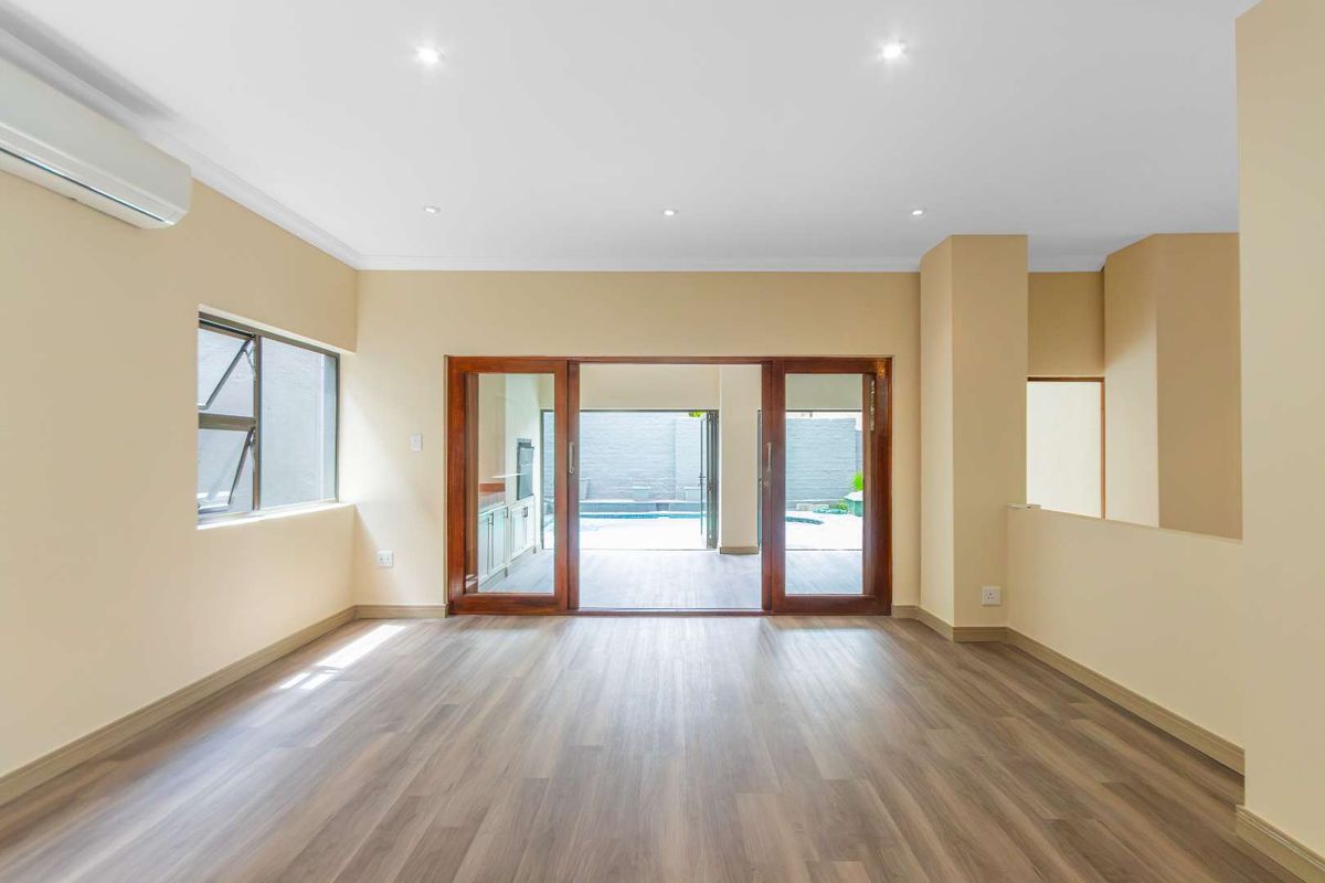 Spacious, light-filled living area featuring modern laminate flooring, recessed lighting, and timber sliding doors providing seamless access to the outdoor patio and pool area.