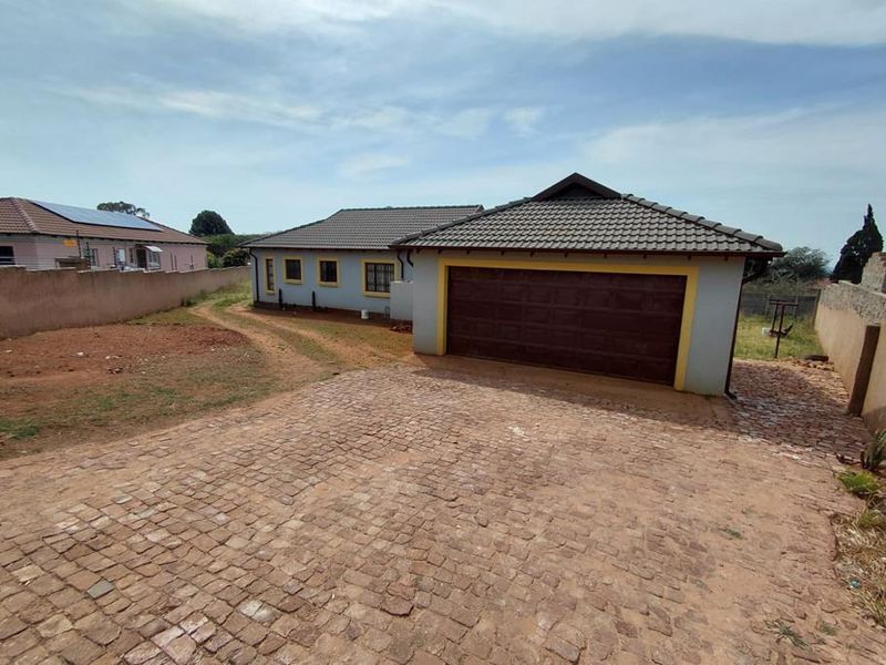 Front view of the property featuring a paved driveway, double garage, and a large, unlandscaped yard area.