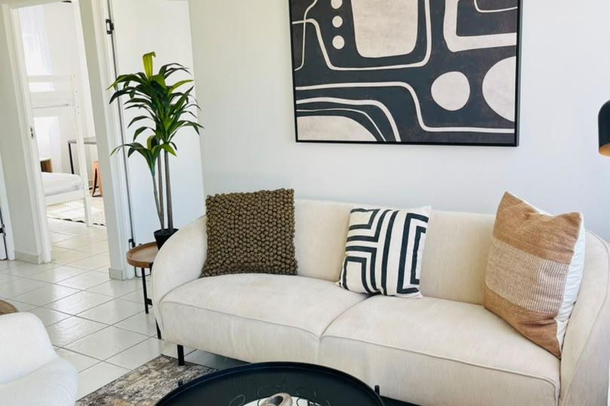 A bright living room featuring tiled flooring and a vaulted ceiling, providing a clean and neutral space with access to adjacent rooms.