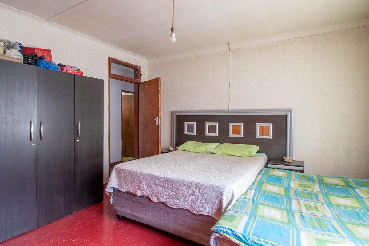 A bedroom featuring a red floor finish, standard door, and basic ceiling light fixture.