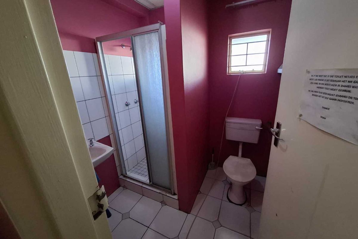 A functional bathroom featuring a shower cubicle, toilet, and basin with tiled flooring and painted walls.