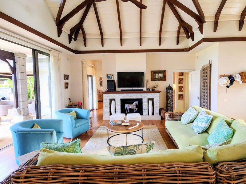 Spacious living room featuring a high vaulted ceiling with exposed timber beams, a stone fireplace, and large sliding glass doors opening to the patio.