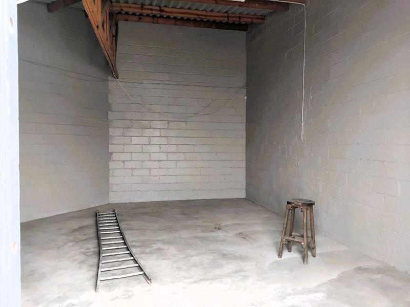 An empty industrial utility space featuring exposed timber roof trusses, concrete block walls, and concrete flooring, suitable for storage or workshop use.