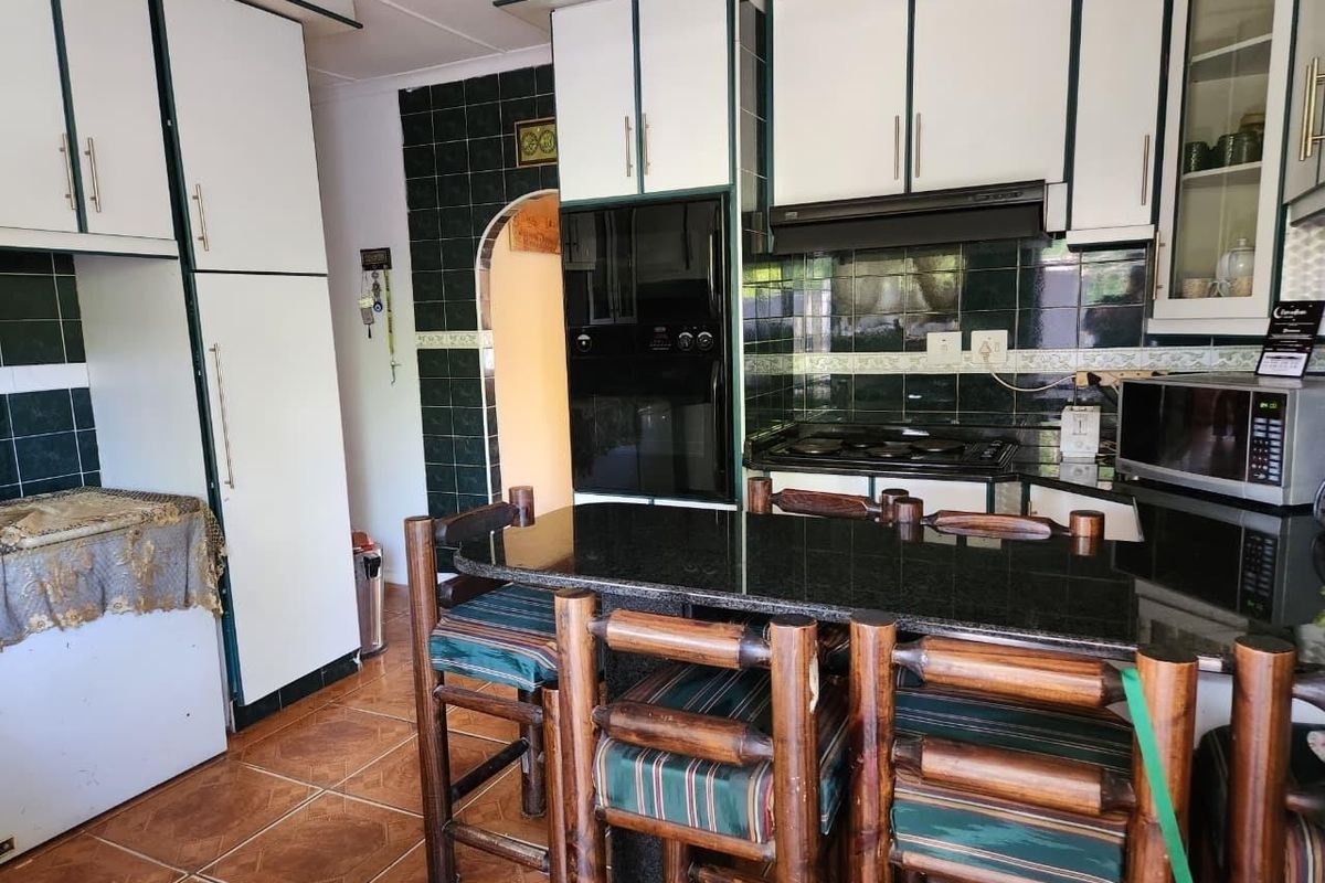 Kitchen featuring white cabinetry, dark granite countertops, tiled backsplash, and built-in cooking appliances with a breakfast bar area.