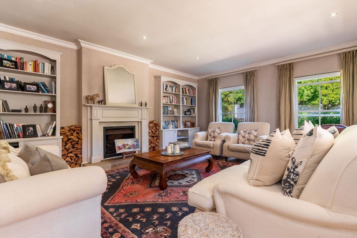 A well-appointed living room featuring a classic fireplace with a mantelpiece, flanked by built-in shelving units and large windows providing natural light.
