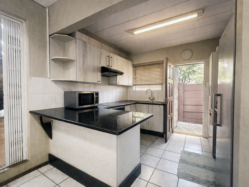 Functional kitchen featuring granite countertops, laminate cabinetry, and direct access to an outdoor area, providing a practical layout for daily meal preparation.