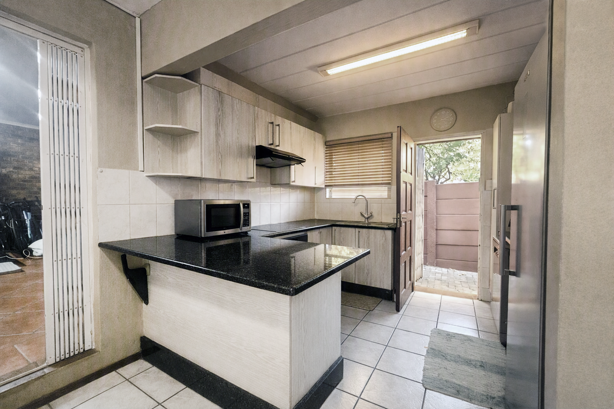 Functional kitchen featuring granite countertops, laminate cabinetry, and direct access to an outdoor area, providing a practical layout for daily meal preparation.
