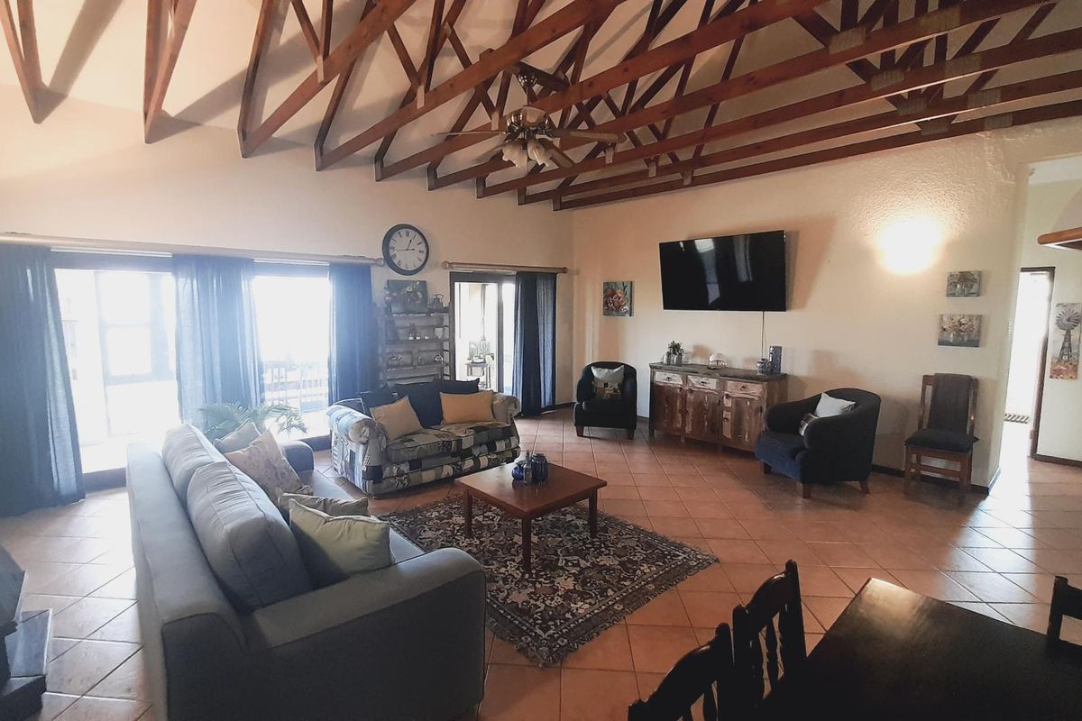 Spacious living room featuring high vaulted ceilings with exposed timber trusses, tiled flooring, and large sliding doors providing access to the outdoor area.