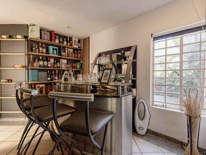 A dedicated bar area featuring a built-in counter, tiled flooring, and a window with security bars, providing a functional space for entertaining.
