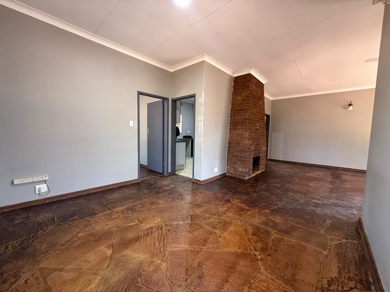 Spacious living area featuring a prominent brick fireplace and unique stone flooring, offering a blank canvas for interior design updates.