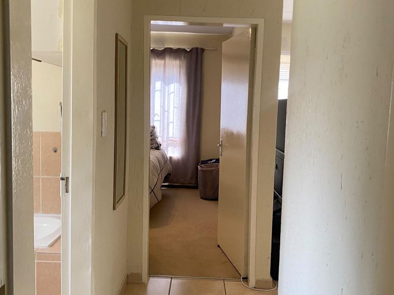 A functional hallway connecting the bathroom and bedroom, featuring tiled flooring and standard internal doors, requiring minor cosmetic updates to wall finishes.