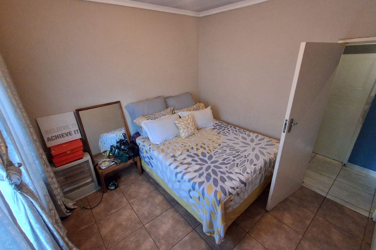 A standard bedroom featuring tiled flooring and neutral wall finishes, providing a functional space with direct access to an adjacent room.