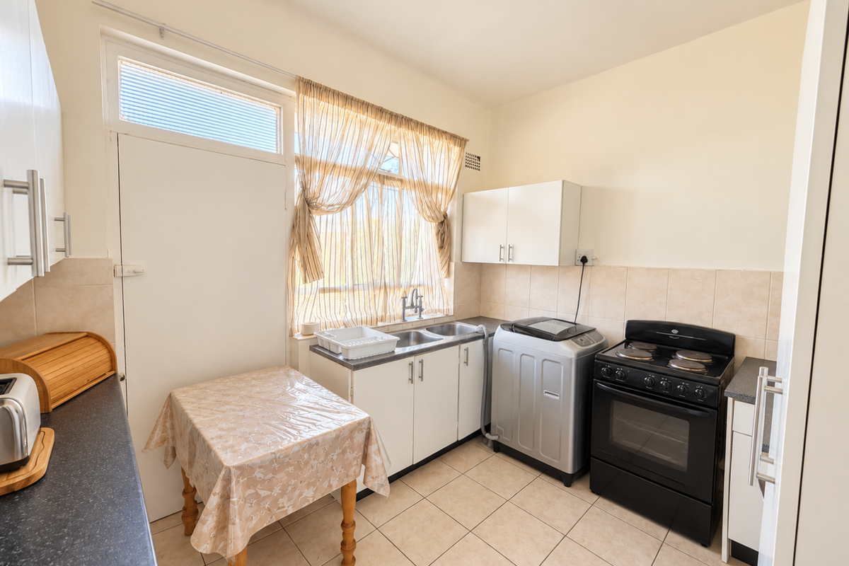 Functional kitchen featuring tiled flooring, built-in cabinetry, a double sink, and a freestanding stove with an extractor fan.