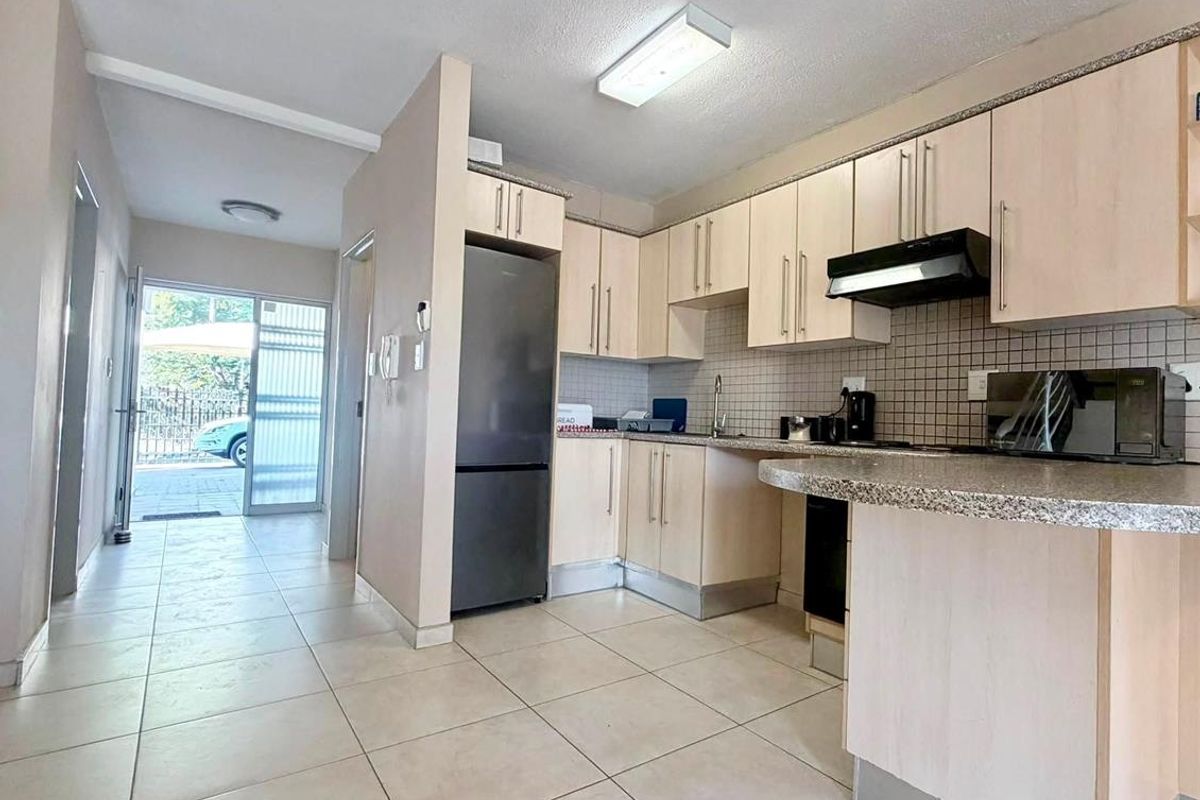 A functional kitchen featuring light wood cabinetry, granite countertops, tiled backsplash, and a breakfast nook, with direct access to the entrance hallway.