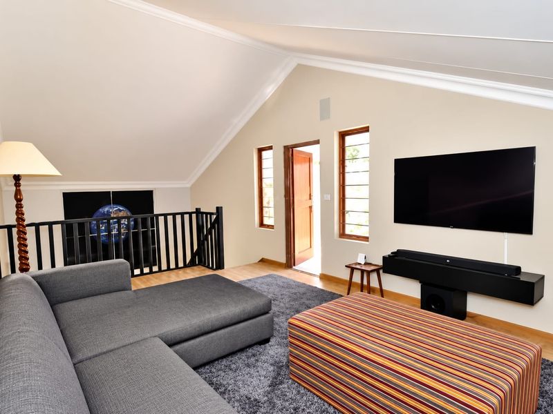 A spacious living area featuring a vaulted ceiling, timber flooring, and a mezzanine-style railing overlooking the lower level.