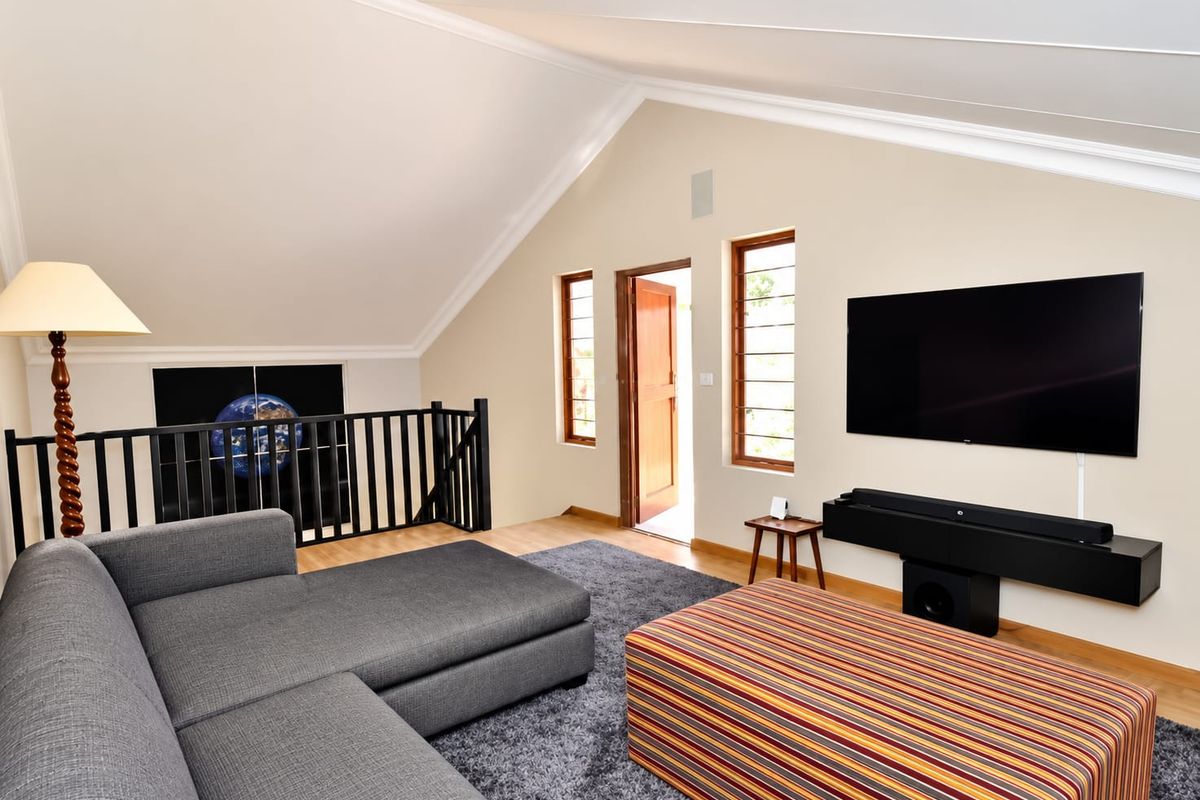 A spacious living area featuring a vaulted ceiling, timber flooring, and a mezzanine-style railing overlooking the lower level.