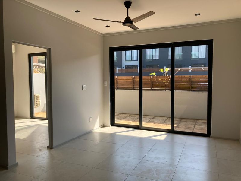 Bright and spacious living area featuring neutral tiled flooring, recessed lighting, a ceiling fan, and large sliding glass doors leading to an outdoor patio.