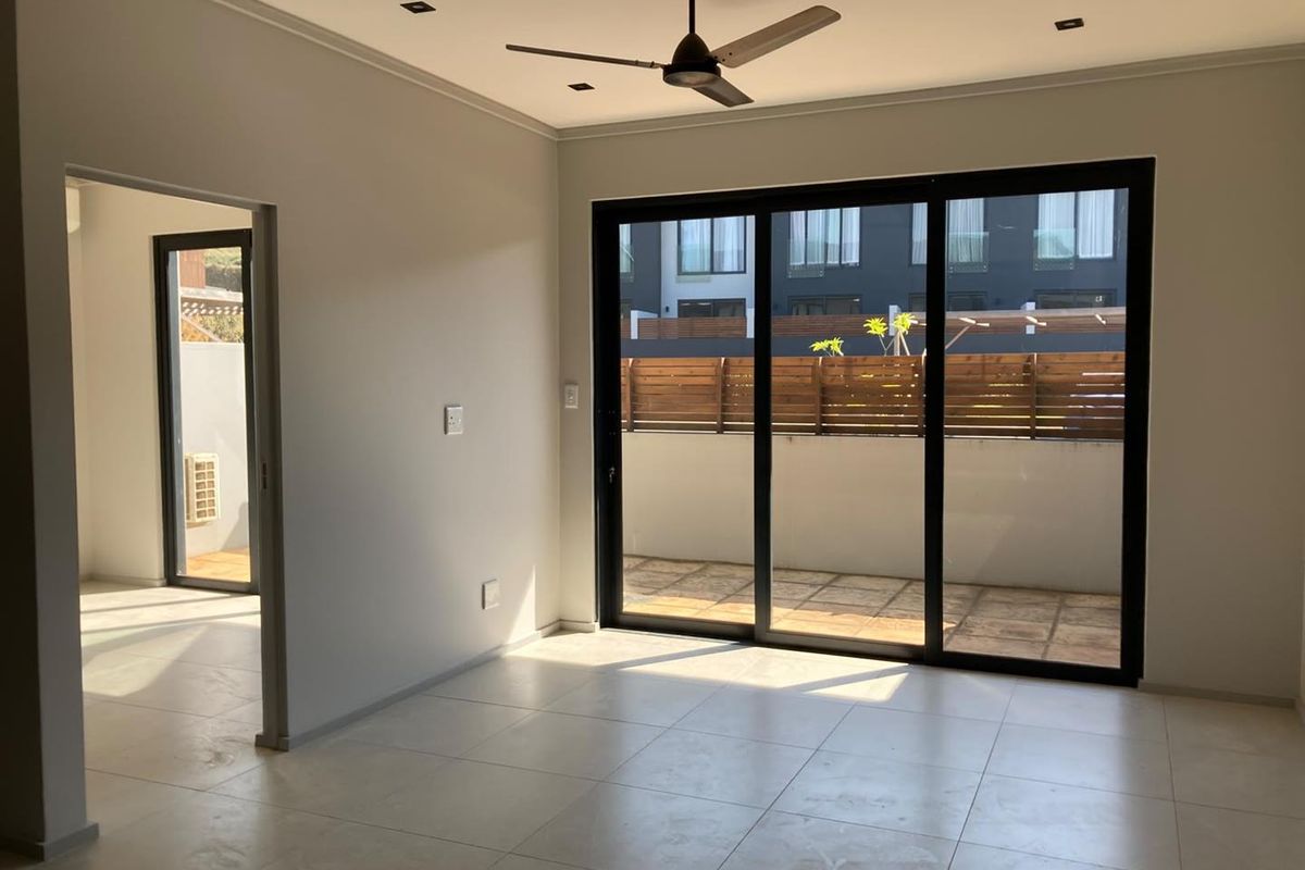 Bright and spacious living area featuring neutral tiled flooring, recessed lighting, a ceiling fan, and large sliding glass doors leading to an outdoor patio.