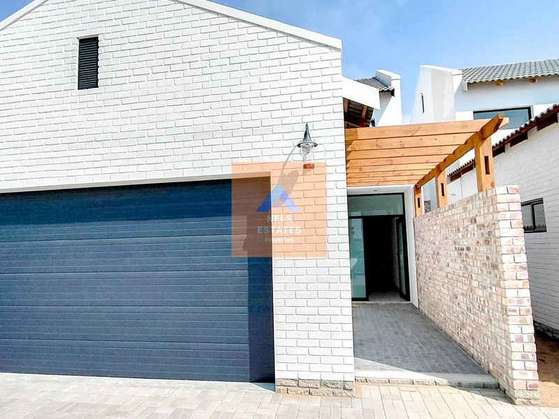 Modern townhouse exterior featuring a clean white brick facade, automated garage door, and a timber pergola over the entrance walkway.
