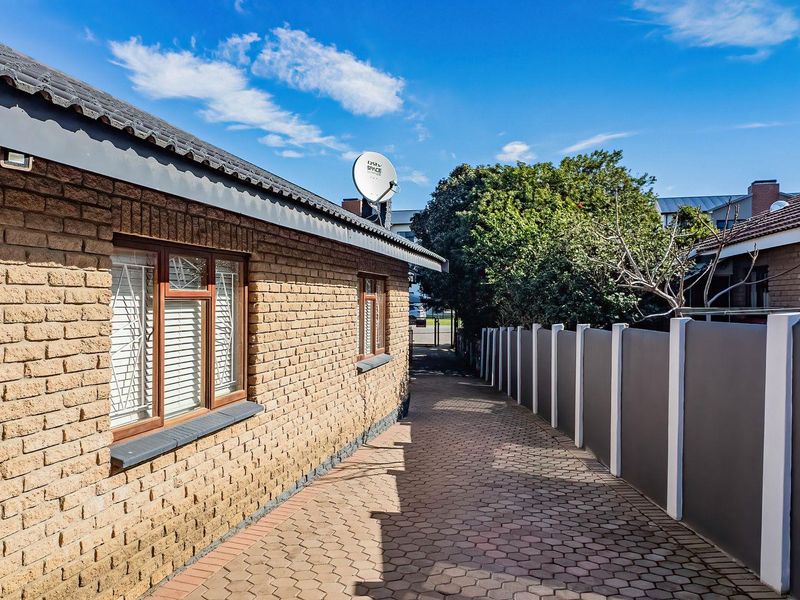 A side walkway featuring face brick exterior walls, a paved path, and a modern boundary wall, providing access along the side of the property.