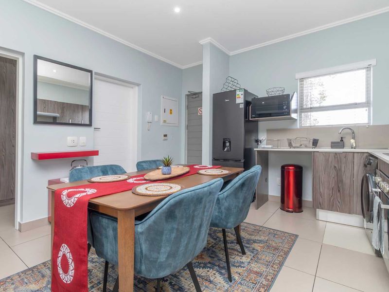 An open-plan living and kitchen area featuring modern cabinetry, integrated appliances, tiled flooring, and a functional layout suitable for dining and relaxation.