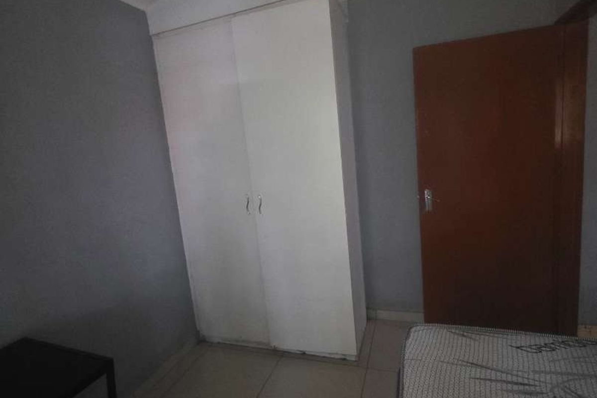 A bedroom featuring built-in white cabinetry, tiled flooring, and a standard wooden door.