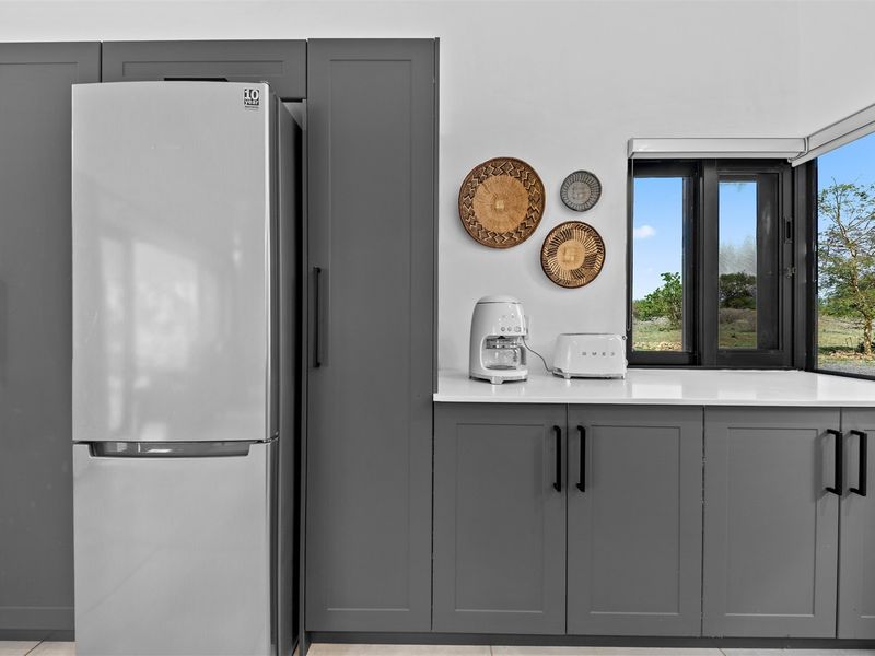 Modern kitchen featuring sleek grey cabinetry, stone countertops, and a window with a scenic outdoor view.