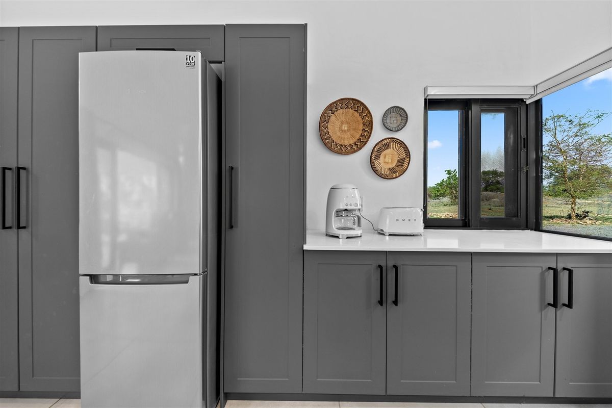 Modern kitchen featuring sleek grey cabinetry, stone countertops, and a window with a scenic outdoor view.