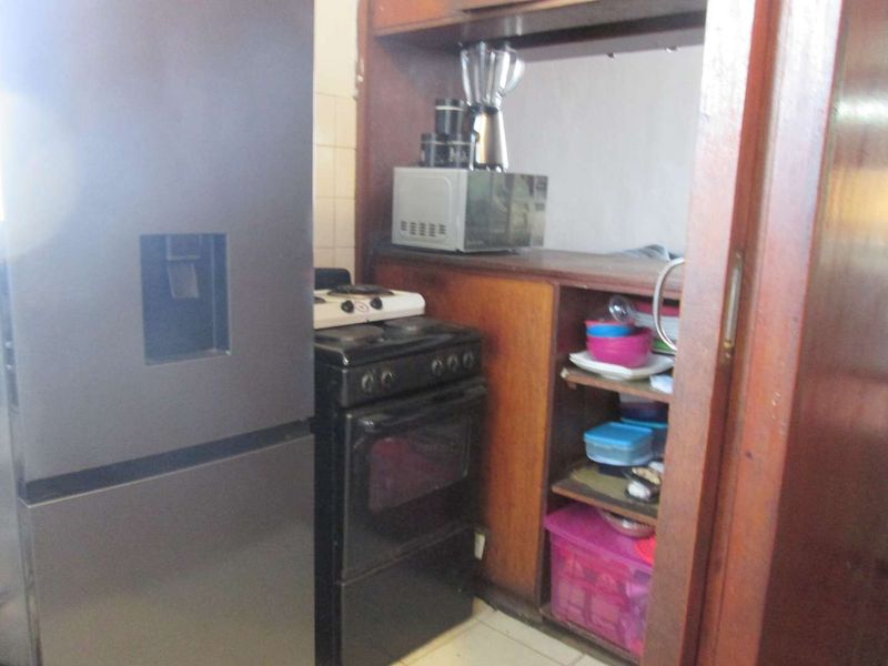 A compact kitchen area featuring built-in wooden cabinetry and a freestanding oven, requiring modernization to improve functionality and aesthetic appeal.