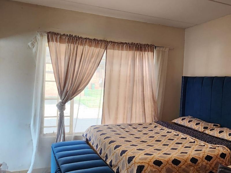 A bedroom featuring a large sliding glass door with curtain rails, providing natural light and access to the exterior.