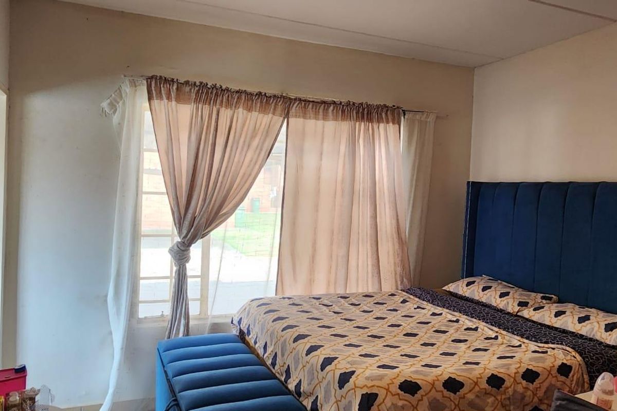 A bedroom featuring a large sliding glass door with curtain rails, providing natural light and access to the exterior.