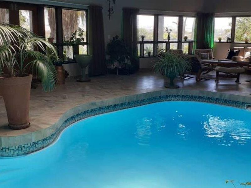 Indoor swimming pool area featuring tiled flooring and large windows, creating a bright and integrated entertainment space.