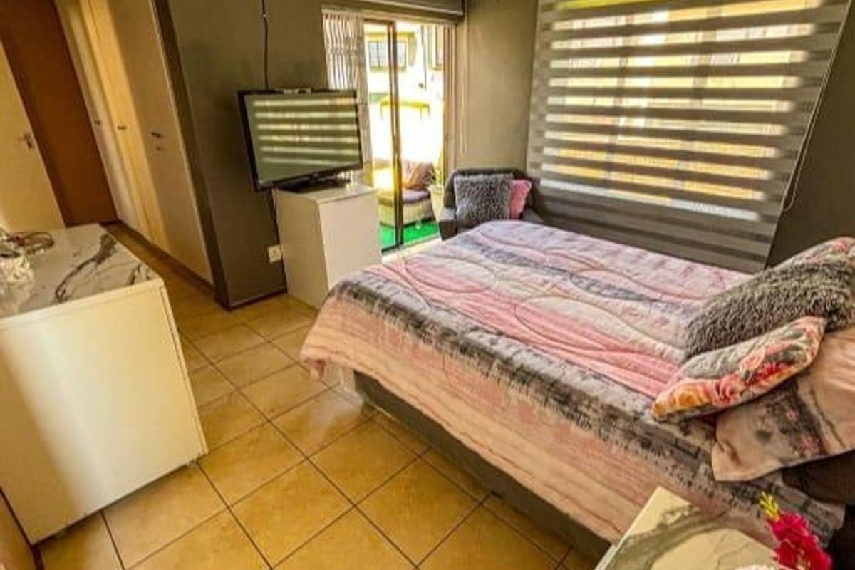 A bedroom featuring tiled flooring, built-in cupboards, and sliding door access to an outdoor patio area.