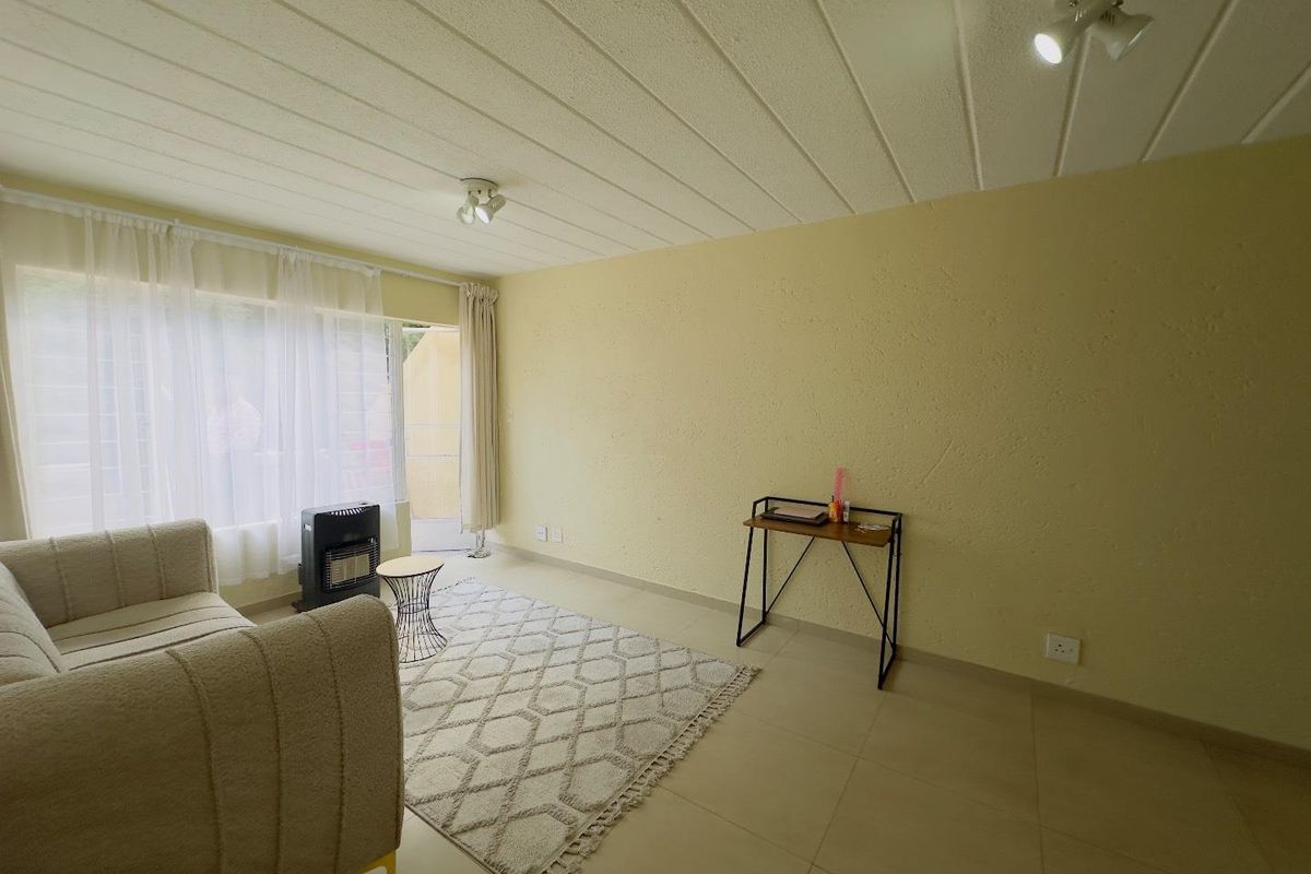 A living room featuring tiled flooring, textured walls, and a sliding glass door providing access to an outdoor area.