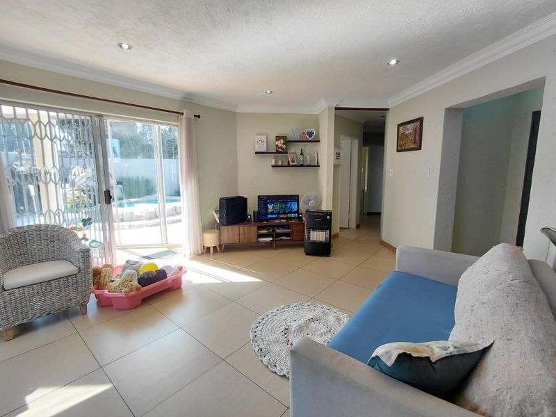 Spacious living room featuring tiled flooring, recessed lighting, and a sliding glass door providing direct access to the outdoor pool area.