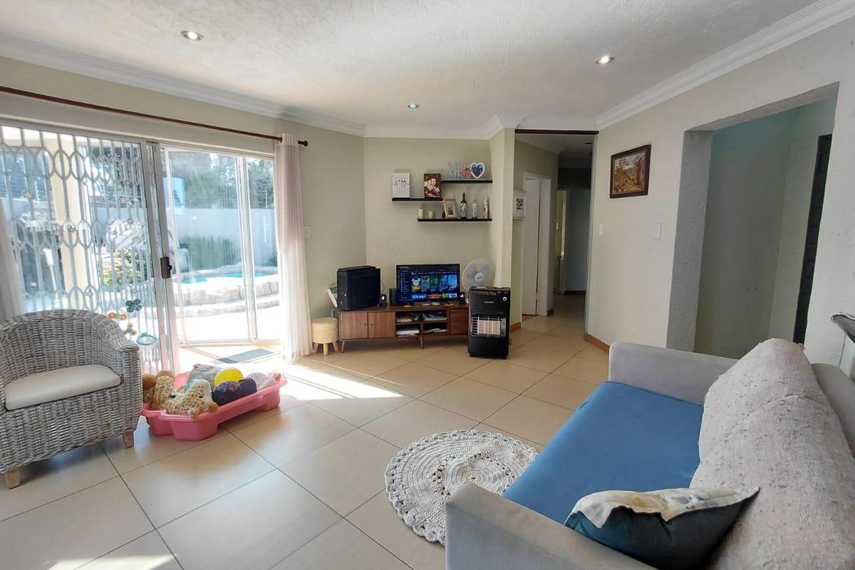 Spacious living room featuring tiled flooring, recessed lighting, and a sliding glass door providing direct access to the outdoor pool area.