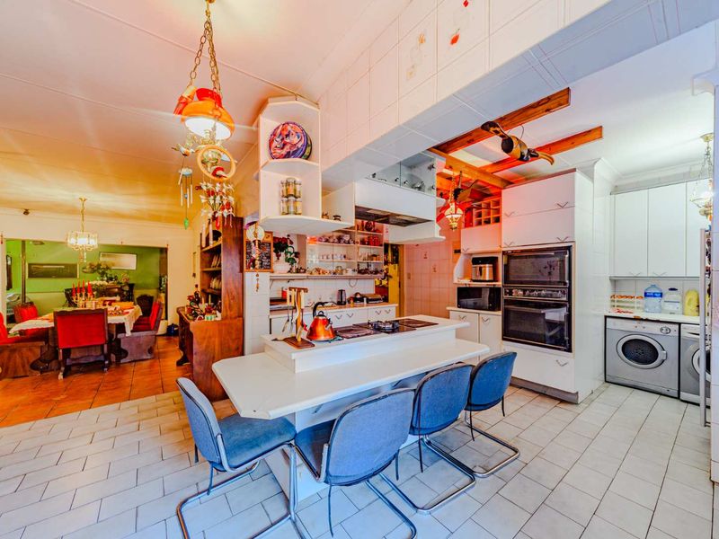 Open-plan kitchen and dining area featuring a central island, built-in double oven, and tiled flooring, offering a functional layout with potential for modern updates.