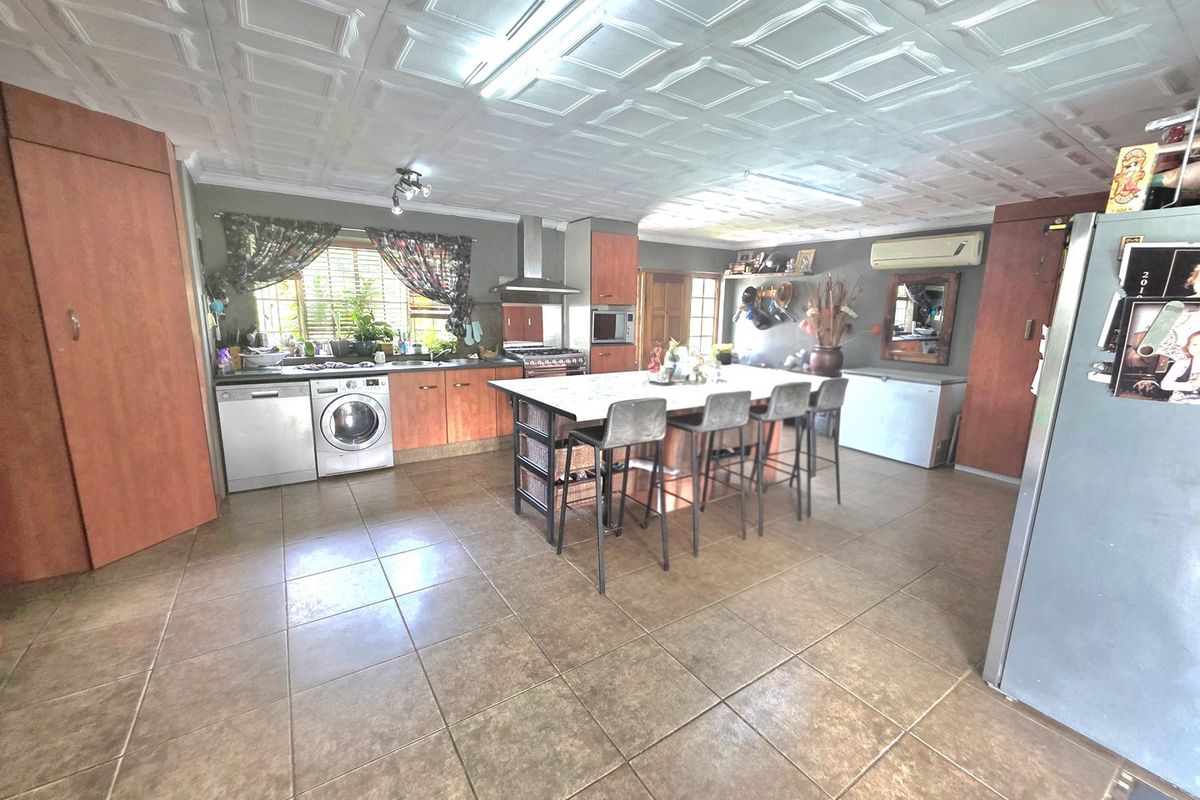 Spacious kitchen featuring a central island, tiled flooring, coffered ceiling, and built-in cabinetry with integrated appliances.