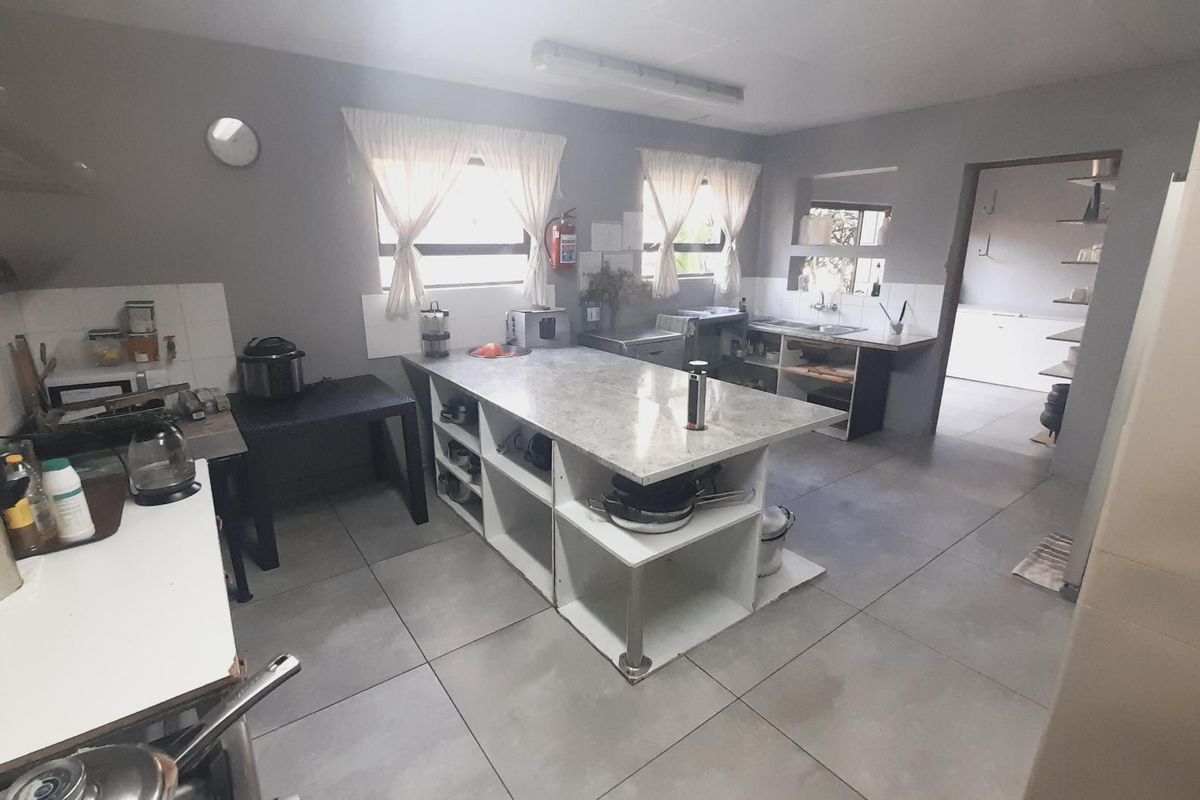 Functional kitchen area featuring a central island with stone countertop, tiled flooring, and built-in storage shelving.