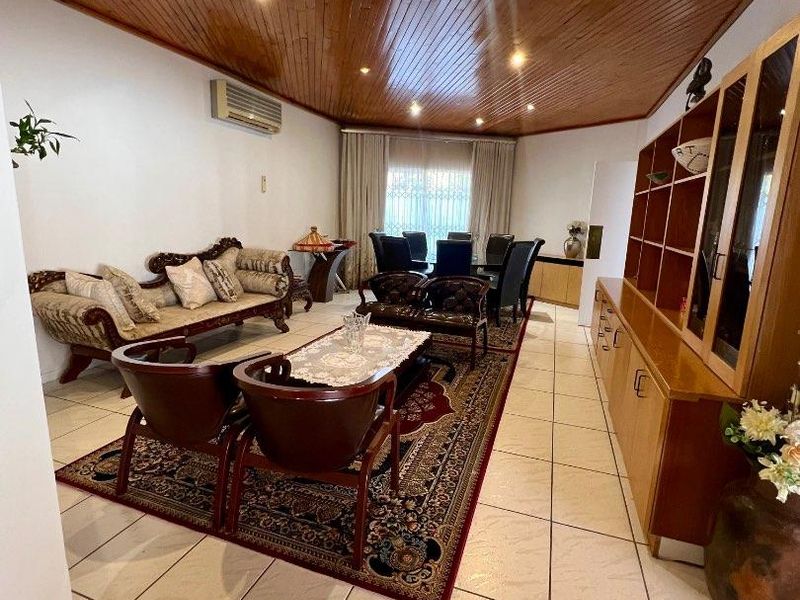 Spacious open-plan living and dining area featuring a distinctive timber-clad vaulted ceiling, ceramic floor tiles, and integrated built-in cabinetry.