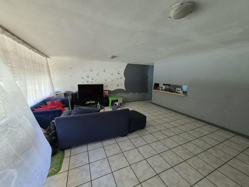 Spacious living area featuring tiled flooring and a convenient pass-through window connecting to the kitchen area.