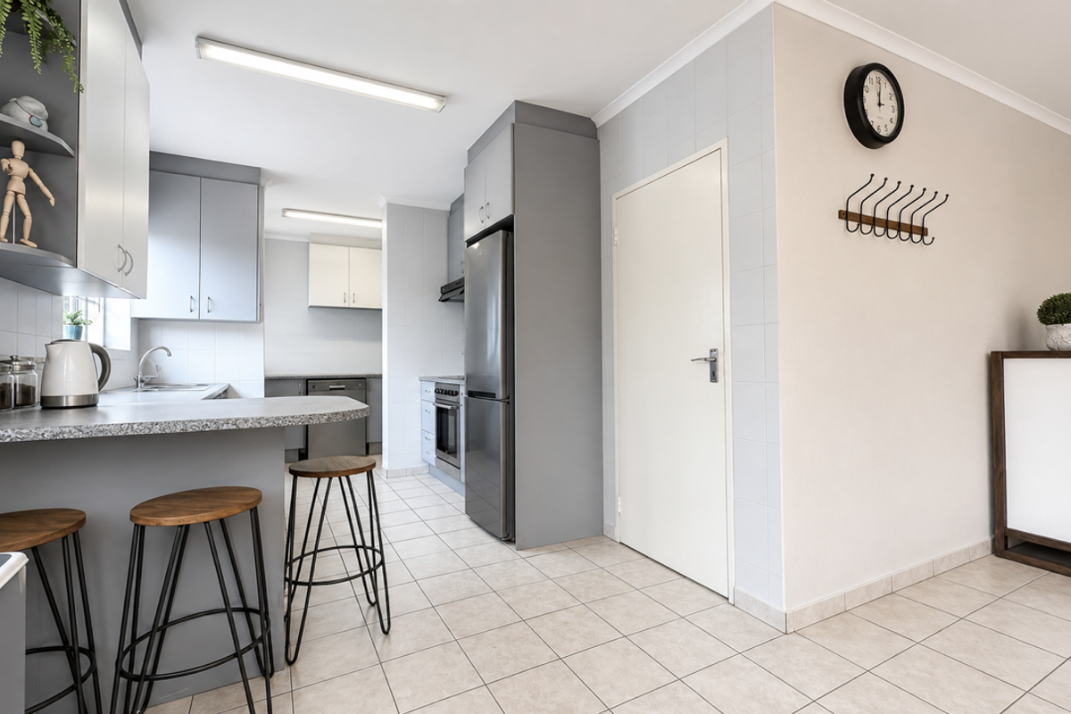 A functional kitchen featuring grey cabinetry, laminate countertops, tiled flooring, and a breakfast bar area, providing a clean and practical workspace.