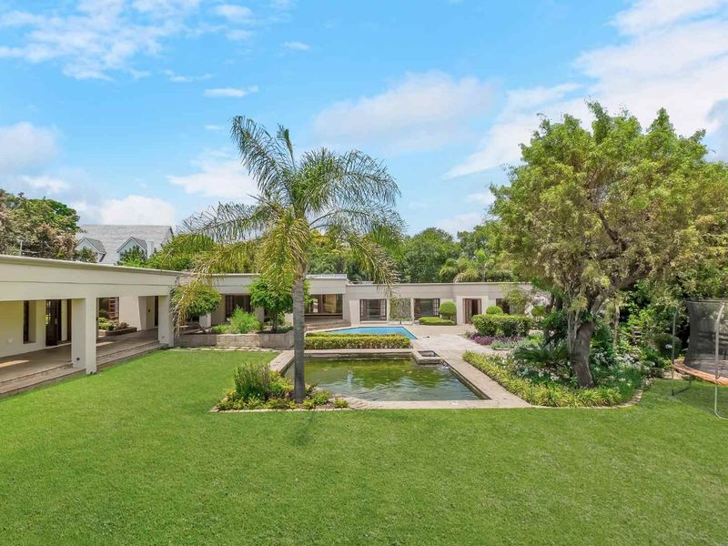 Spacious rear garden featuring a swimming pool, a decorative koi pond, a covered patio area, and mature landscaping.
