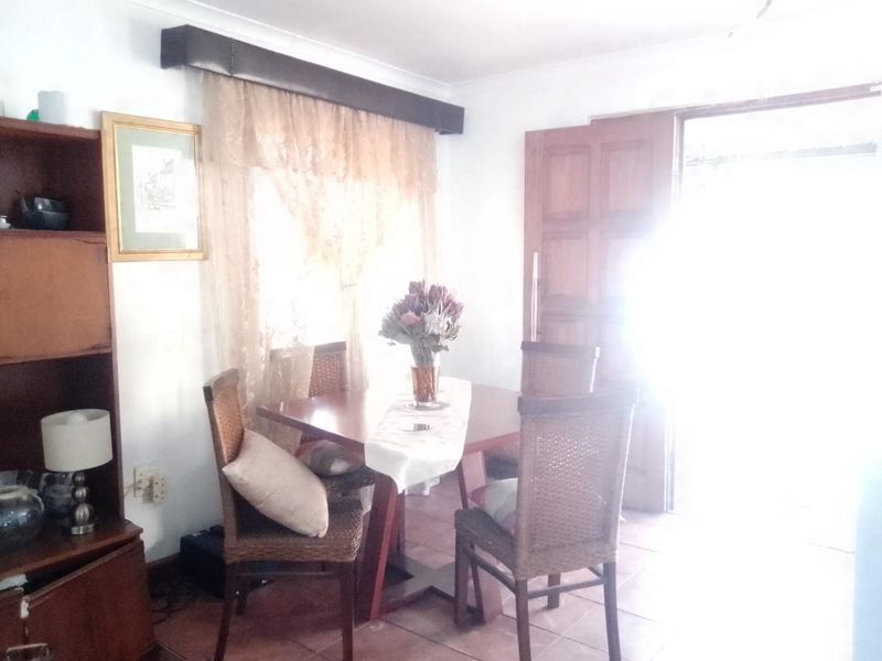 A dining area featuring tiled flooring and a timber door, with natural light entering from the adjacent doorway.