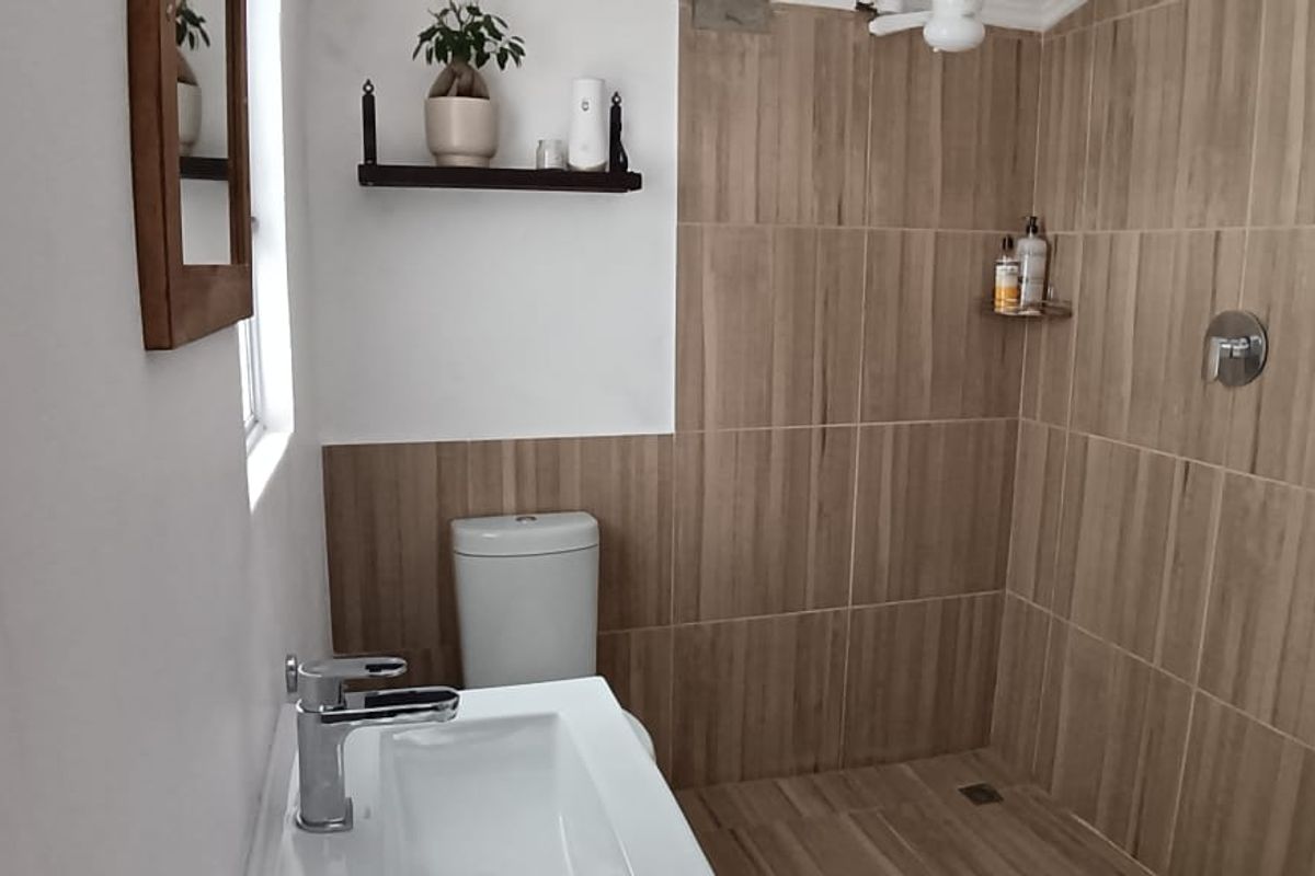 A modern bathroom featuring wood-look tiled shower walls, a contemporary vanity basin, and a sleek toilet.