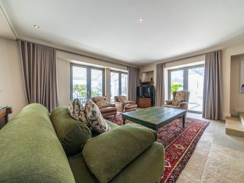 Spacious living room featuring stone flooring, recessed lighting, and multiple sets of double-glazed french doors providing ample natural light and access to the outdoors.